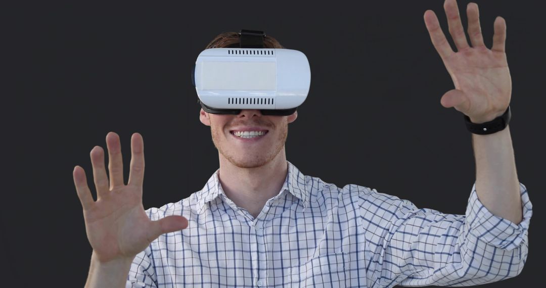 Smiling man wearing VR headset reaching forward with hands exploring virtual interface