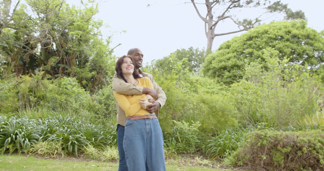 Diverse Couple Embracing in Lush Garden Setting with Smiles