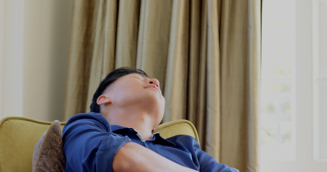 Thoughtful Asian Man Relaxing by Window During Daytime