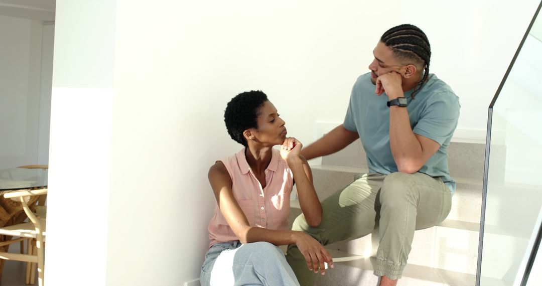 Diverse Couple Having Thoughtful Conversation on Staircase in Modern Home