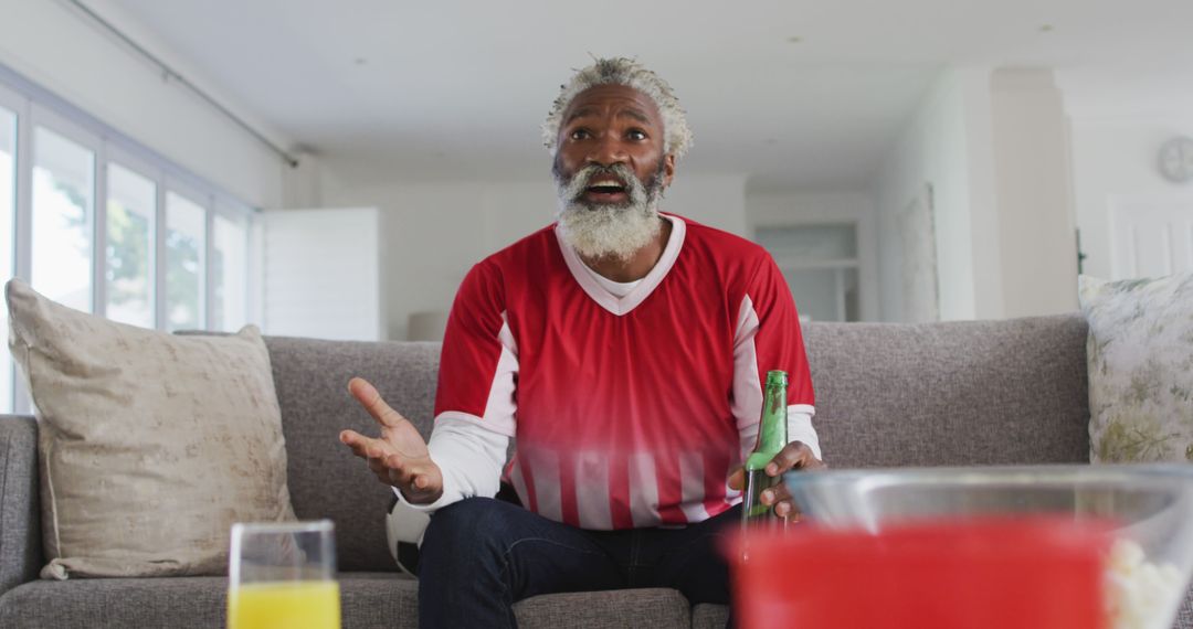 Elderly man excitedly watching sports game on TV at home - Free Images, Stock Photos and Pictures on Pikwizard.com