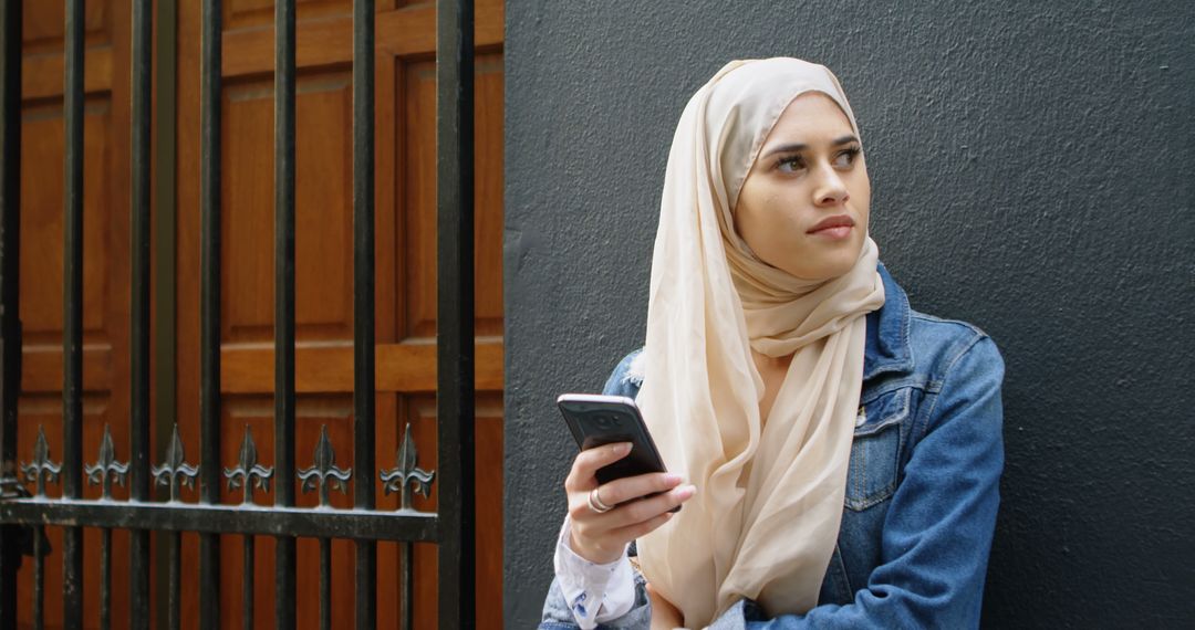 Confident Young Woman Wearing Hijab Using Smartphone Outdoors - Free Images, Stock Photos and Pictures on Pikwizard.com