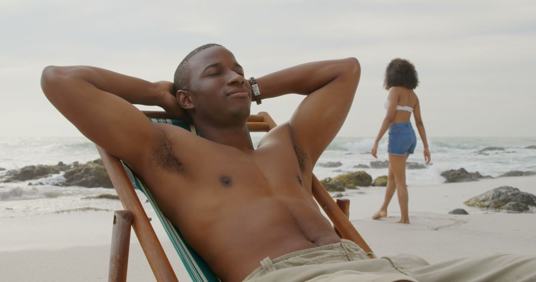 Relaxed Man Enjoying Beach as Woman Walks Along Shoreline