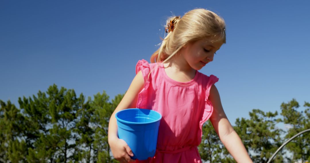 Little Girl Playing Outdoors on Sunny Day Holding Blue Bucket - Free Images, Stock Photos and Pictures on Pikwizard.com