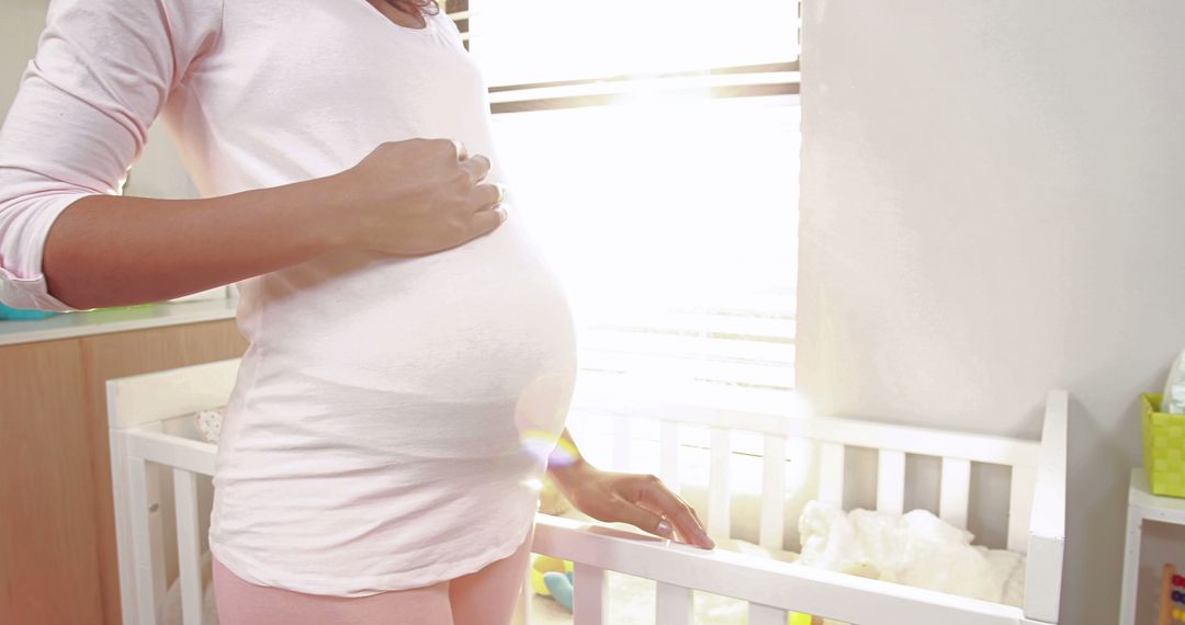 Pregnant Woman Standing by Crib in Sunlit Room - Free Images, Stock Photos and Pictures on Pikwizard.com