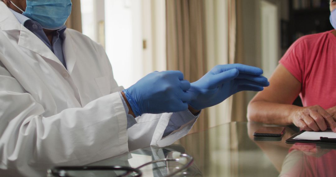 Doctor Putting On Blue Gloves Next To Patient In Medical Office - Free Images, Stock Photos and Pictures on Pikwizard.com