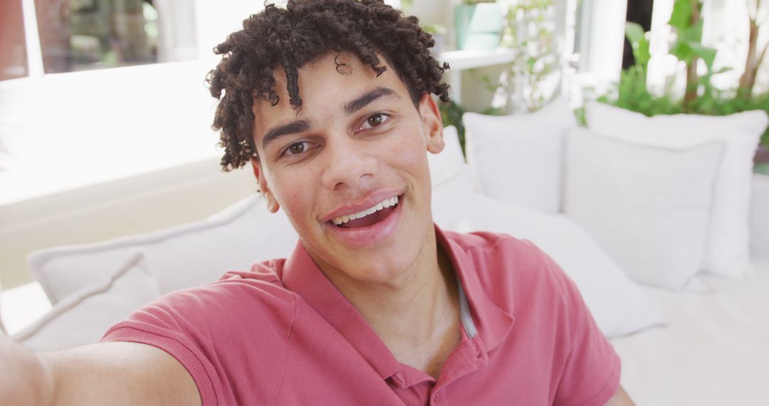 Young Man Smiling and Taking Selfie on Couch in Bright Indoor Setting - Free Images, Stock Photos and Pictures on Pikwizard.com