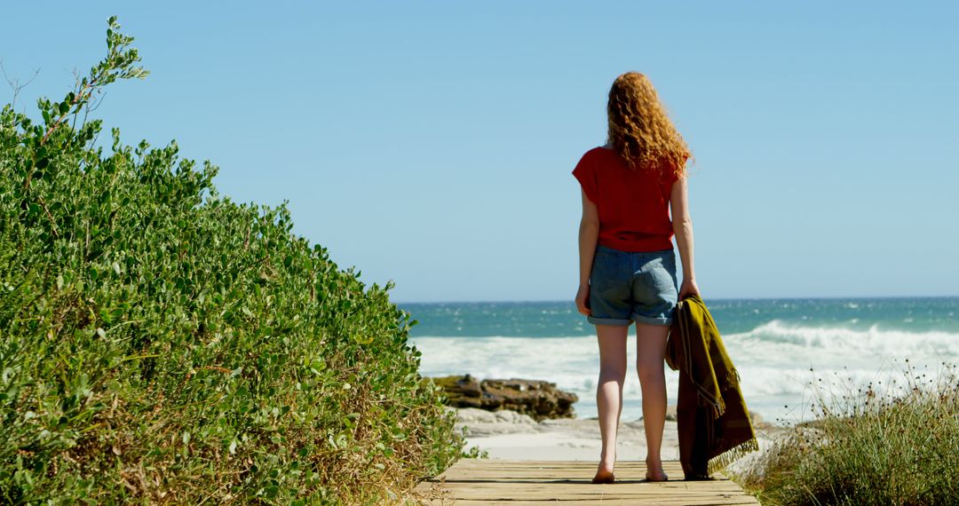 Woman with Red Hair Standing on Beach Path Looking at Ocean - Free Images, Stock Photos and Pictures on Pikwizard.com