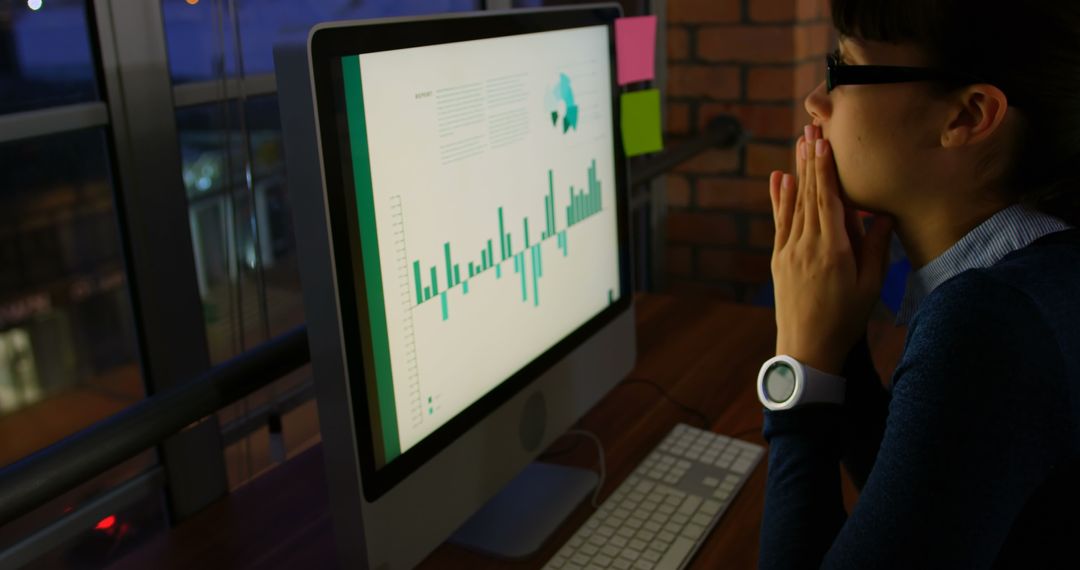 Businesswoman Analyzing Graphs on Computer at Night Office