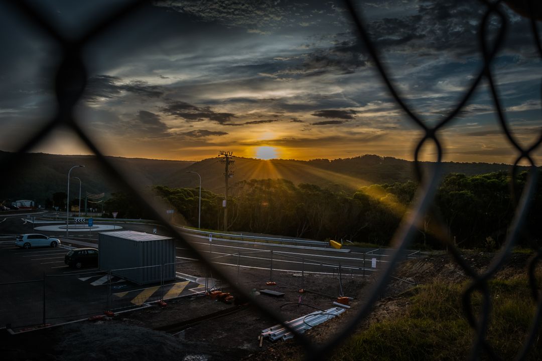 Dramatic Sunset Over Hilly Landscape Viewed Through Wire Fence - Free Images, Stock Photos and Pictures on Pikwizard.com