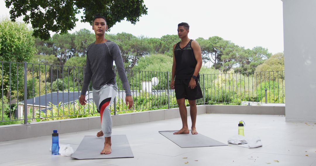 Biracial gay male couple standing on terrace practicing yoga - Free Images, Stock Photos and Pictures on Pikwizard.com