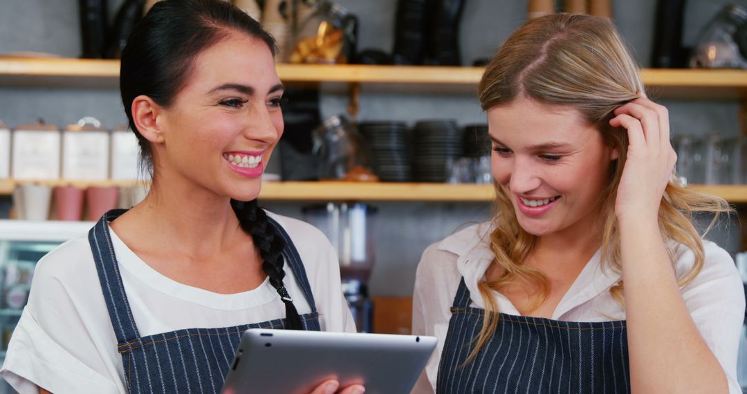 Smiling Female Baristas Using Tablet in Coffee Shop - Free Images, Stock Photos and Pictures on Pikwizard.com