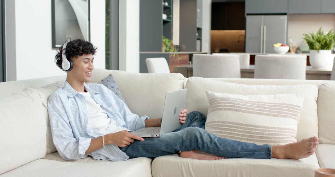 Young Man Relaxing at Home with Laptop and Headphones