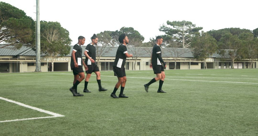 Soccer Players in Black Uniforms Warming Up on Field