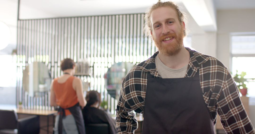 Happy Barber Wearing Apron Smiling in Modern Salon - Free Images, Stock Photos and Pictures on Pikwizard.com