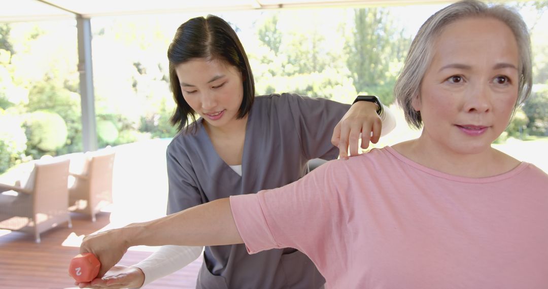 Physical Therapist Assisting Senior Woman with Arm Exercise Using Dumbbell