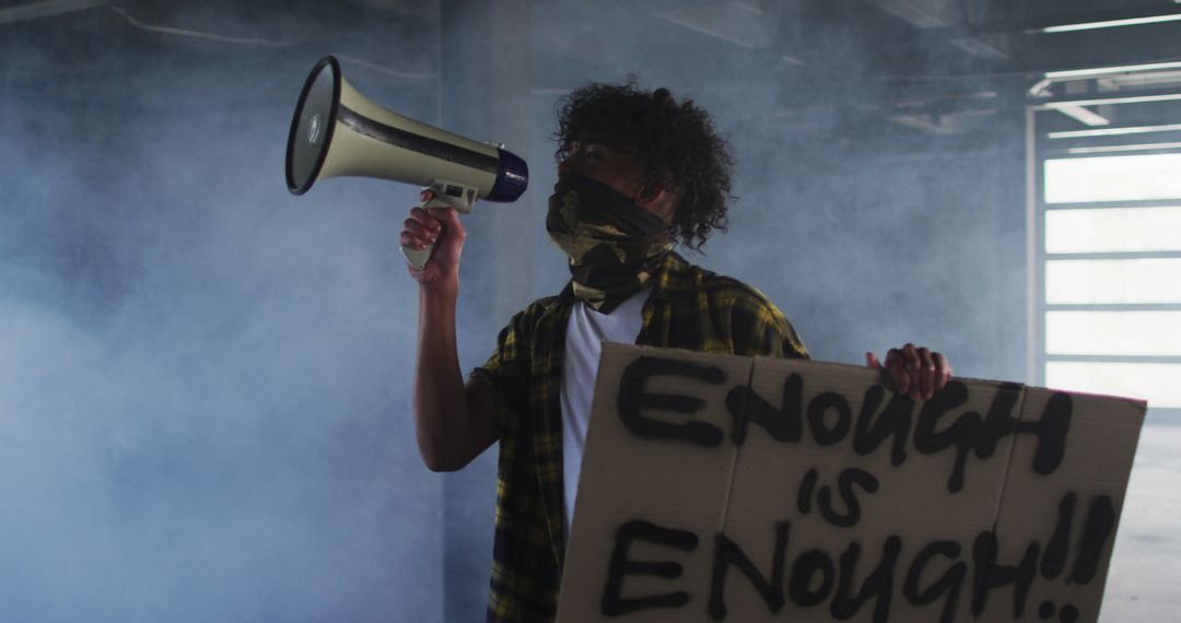 Protester with megaphone holding sign in smoky environment - Free Images, Stock Photos and Pictures on Pikwizard.com