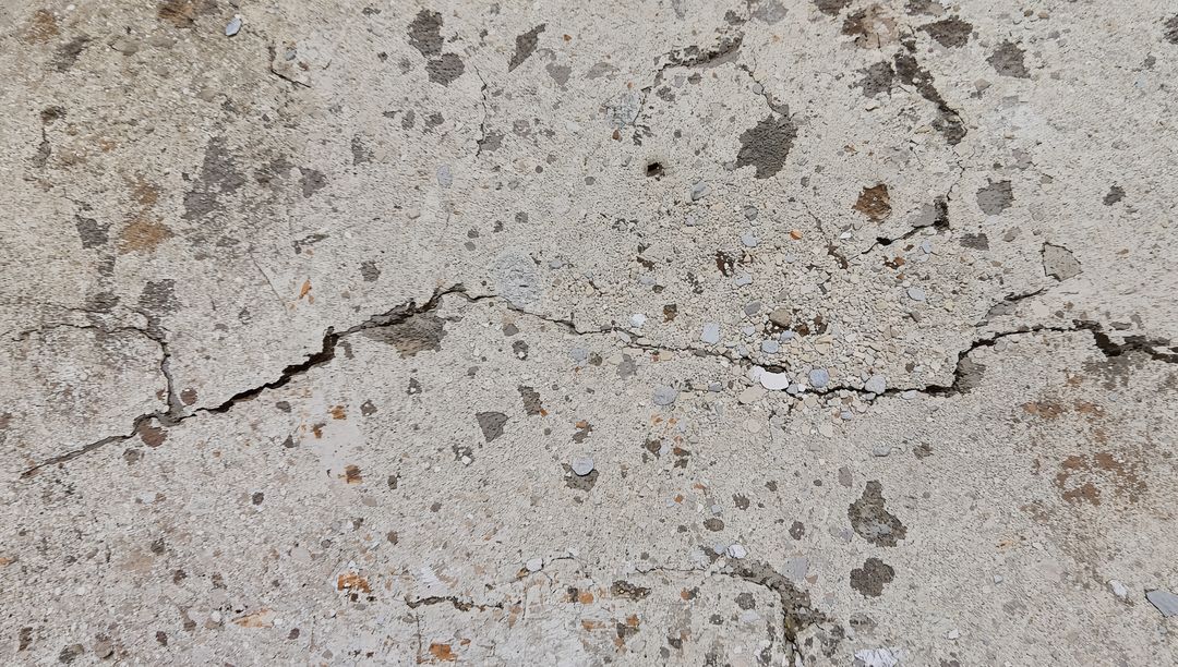 Worn Concrete Slab Showing Cracks, Exposed Aggregate and Weathered Pavement Texture