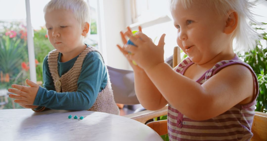 Caucasian Children Playing with Clay at Home Table with Sunlight