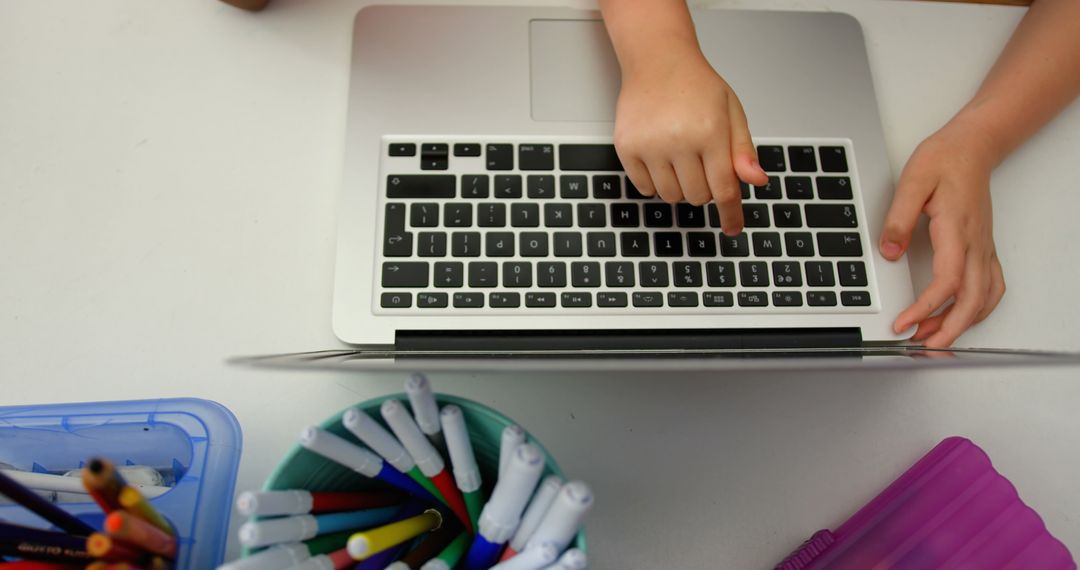 Child Learning on Laptop with Stationery in Classroom