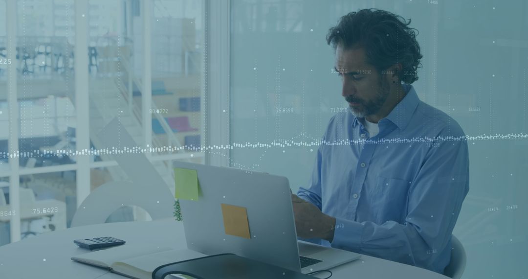 Man Analyzing Financial Data on Laptop in Modern Office