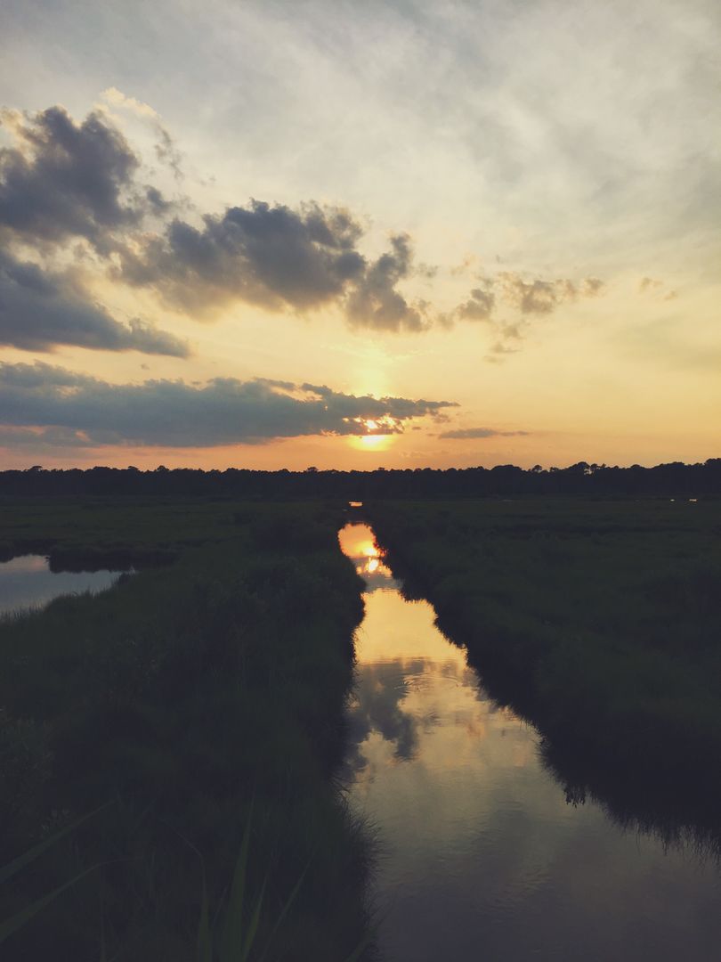 Serene Sunset Over Tranquil River and Lush Green Grasslands - Free Images, Stock Photos and Pictures on Pikwizard.com