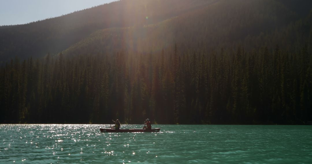 Two people canoeing on serene mountain lake at twilight - Free Images, Stock Photos and Pictures on Pikwizard.com