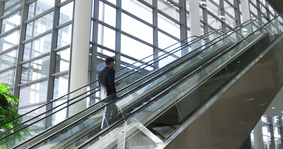 Businessman on Escalator in Modern Office Building - Free Images, Stock Photos and Pictures on Pikwizard.com