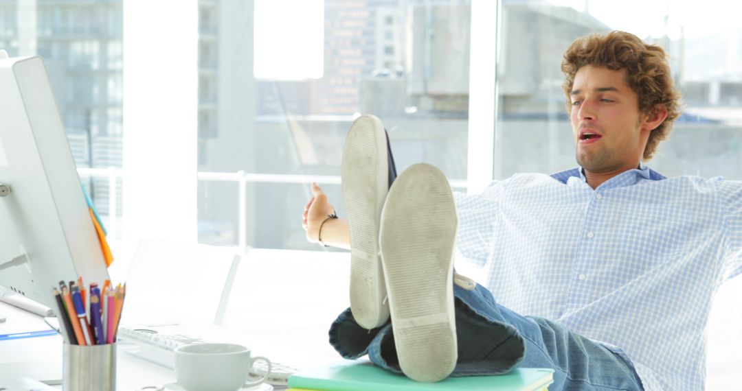 Relaxed Businessman With Feet On Desk Stretching In Office - Free Images, Stock Photos and Pictures on Pikwizard.com