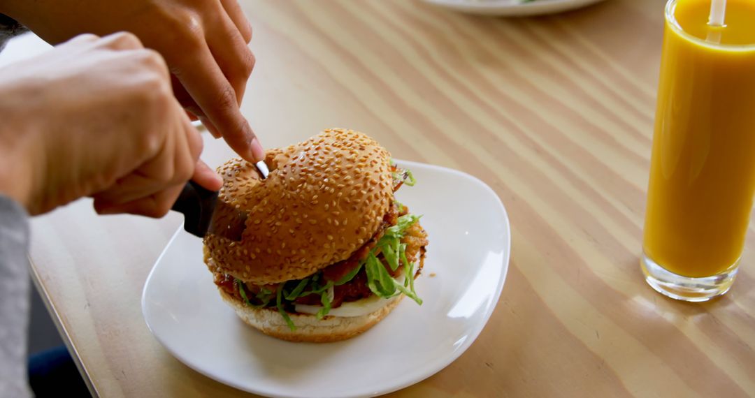 Person Cutting Veggie Burger with Drink on Table - Free Images, Stock Photos and Pictures on Pikwizard.com