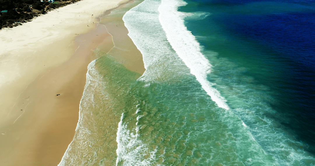 Transparent Waves Hitting Pristine Sandy Beach from Above