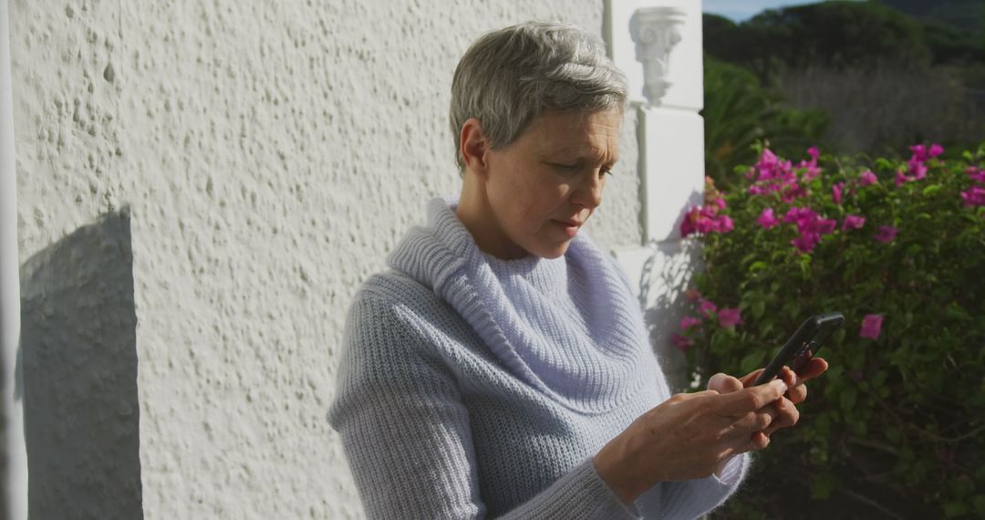 Senior Woman Texting on Smartphone Outdoors in Garden - Free Images, Stock Photos and Pictures on Pikwizard.com