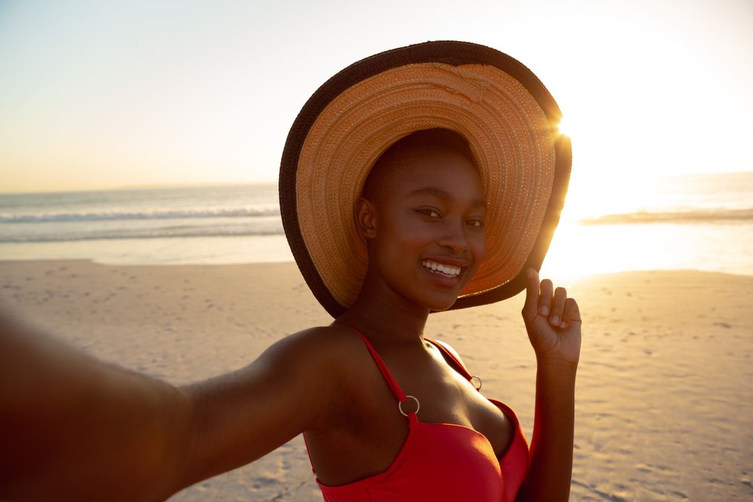 Smiling Woman in Sun Hat Taking Selfie on Beach at Sunset - Free Images, Stock Photos and Pictures on Pikwizard.com