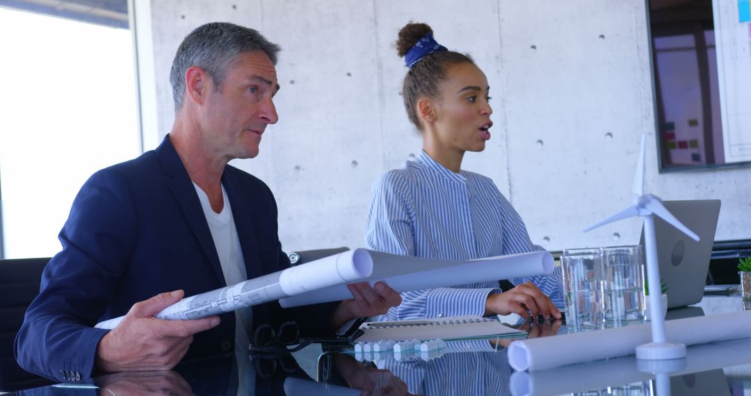 Diverse Business Team Collaborating Over Blueprints in Modern Office