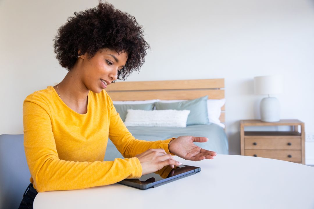 Relaxed Woman in Mustard Top Using Tablet in Cozy Bedroom Setting