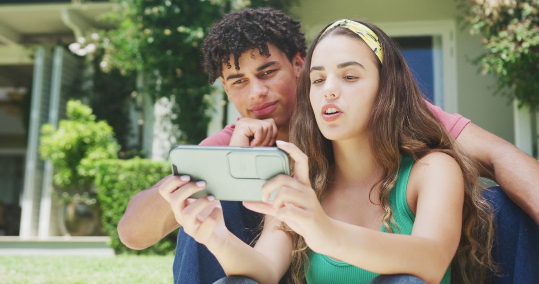 Teenagers Interacting with Smartphone Outdoors on Sunny Day - Free Images, Stock Photos and Pictures on Pikwizard.com