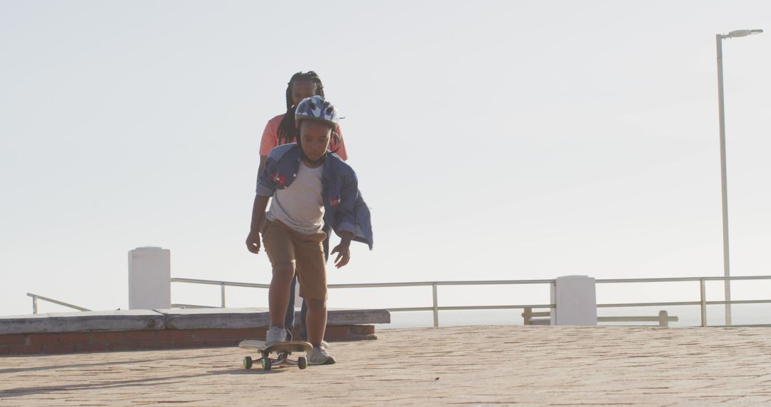 Young Boy Riding Skateboard with Friend on Sunny Day - Free Images, Stock Photos and Pictures on Pikwizard.com