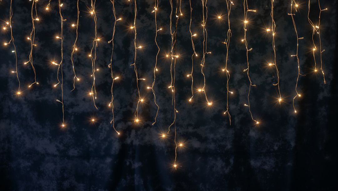 Warm White Fairy Lights Hanging in Vertical Strands on Dark Backdrop for Event Decor