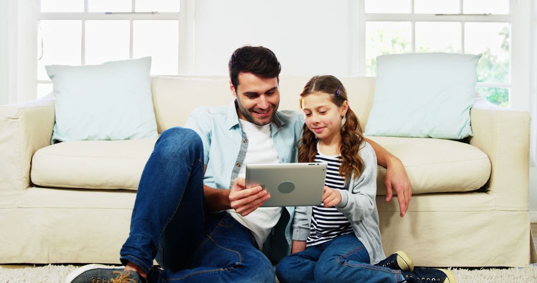 Father and Daughter Using Tablet Together in Living Room - Free Images, Stock Photos and Pictures on Pikwizard.com