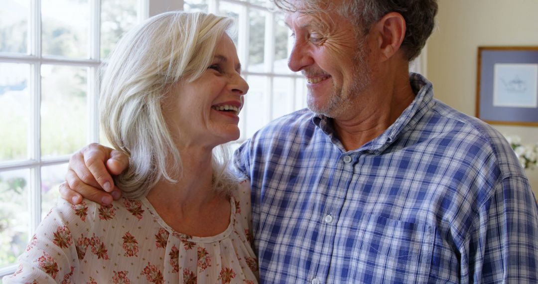 Senior Couple Embracing and Smiling in Sunlit Room - Free Images, Stock Photos and Pictures on Pikwizard.com