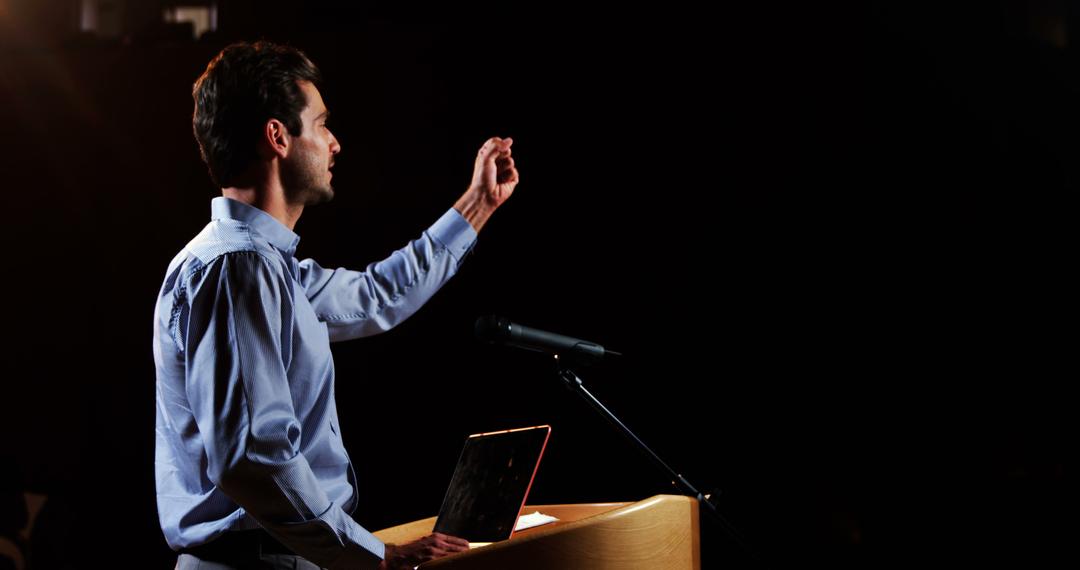 Confident Man Giving Public Speech on Stage Behind Podium - Free Images, Stock Photos and Pictures on Pikwizard.com