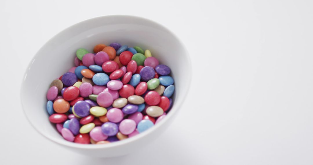 Colorful Candy Coated Buttons in White Bowl on White Background - Free Images, Stock Photos and Pictures on Pikwizard.com