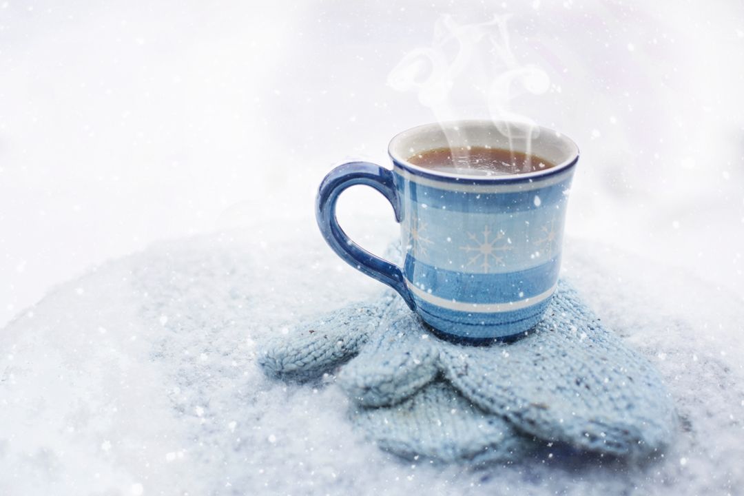 Warm Beverage in a Blue Striped Mug on Cozy Winter Gloves with Snow Falling - Free Images, Stock Photos and Pictures on Pikwizard.com