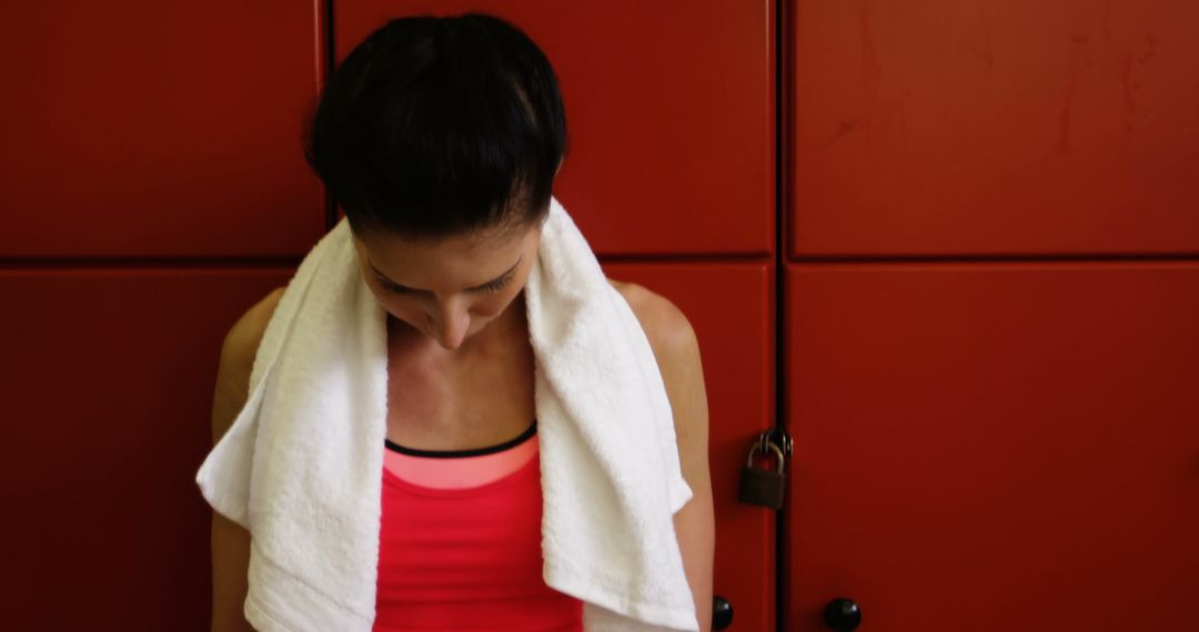 Woman wearing workout attire with towel in gym locker room - Free Images, Stock Photos and Pictures on Pikwizard.com