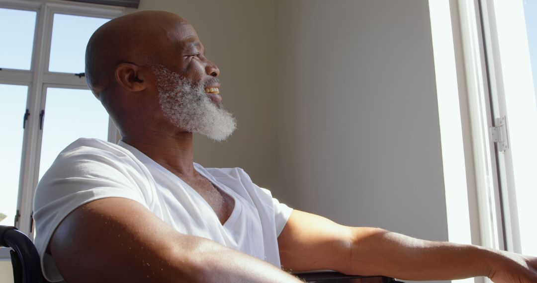 Senior Black Man in Wheelchair Smiling by Sunlit Window - Free Images, Stock Photos and Pictures on Pikwizard.com