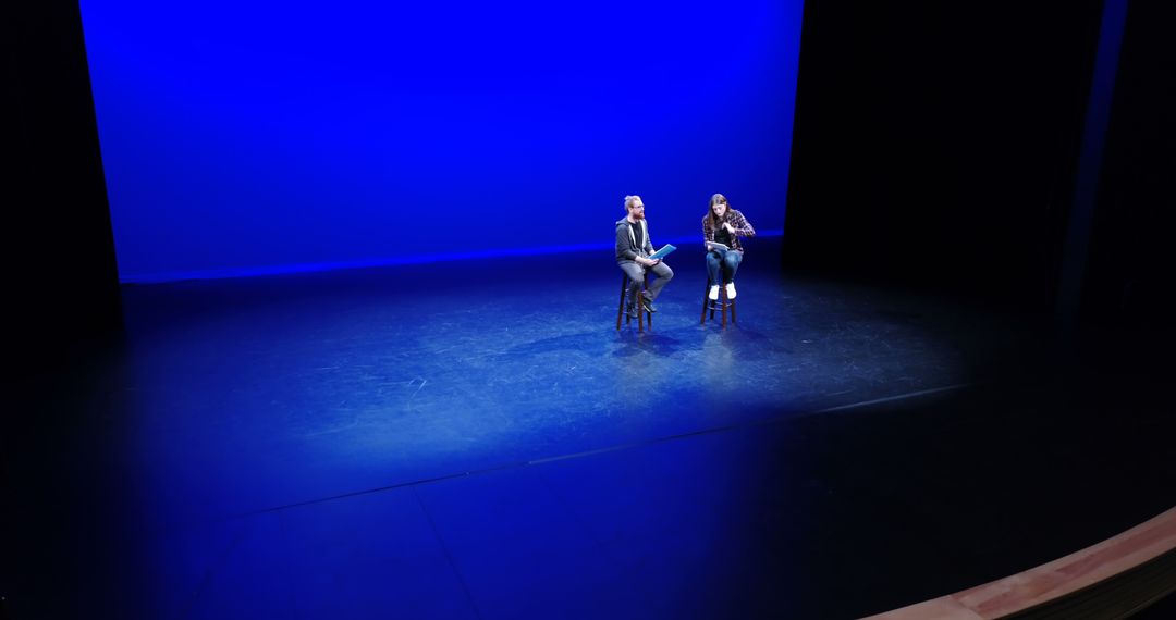 Two People Having Conversation on Stage under Blue Lighting - Free Images, Stock Photos and Pictures on Pikwizard.com