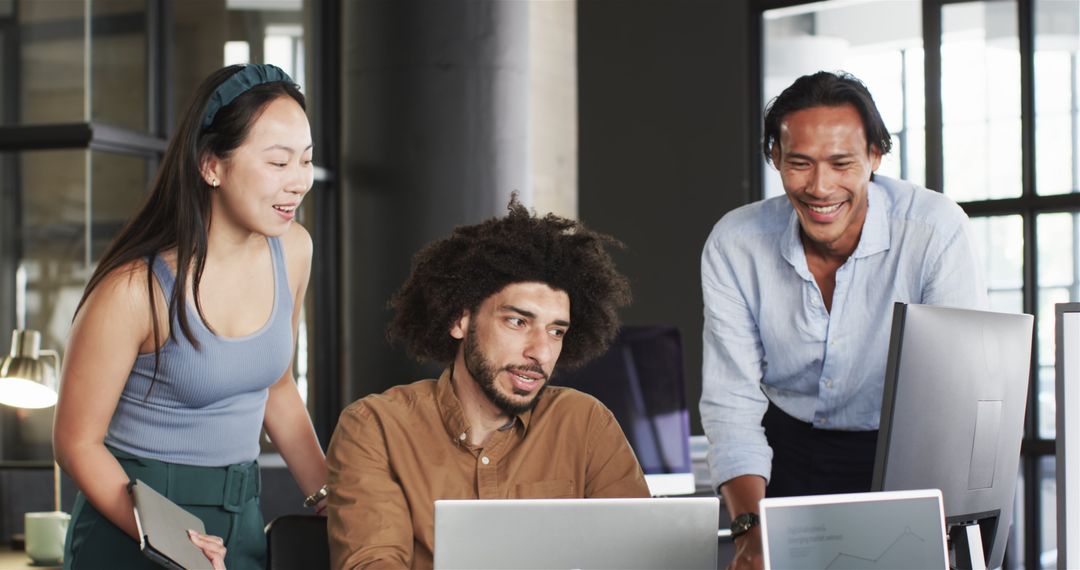 Diverse Team Collaborating Enthusiastically Around Computer