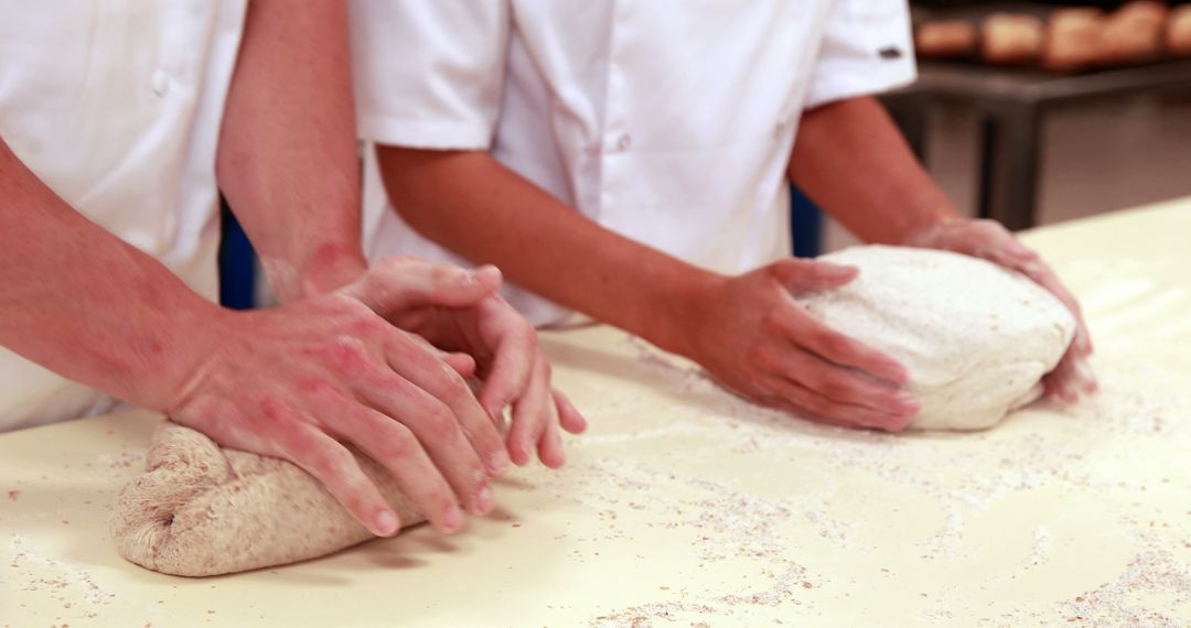 Professional Bakers Kneading Dough on Floured Surface in Bakery