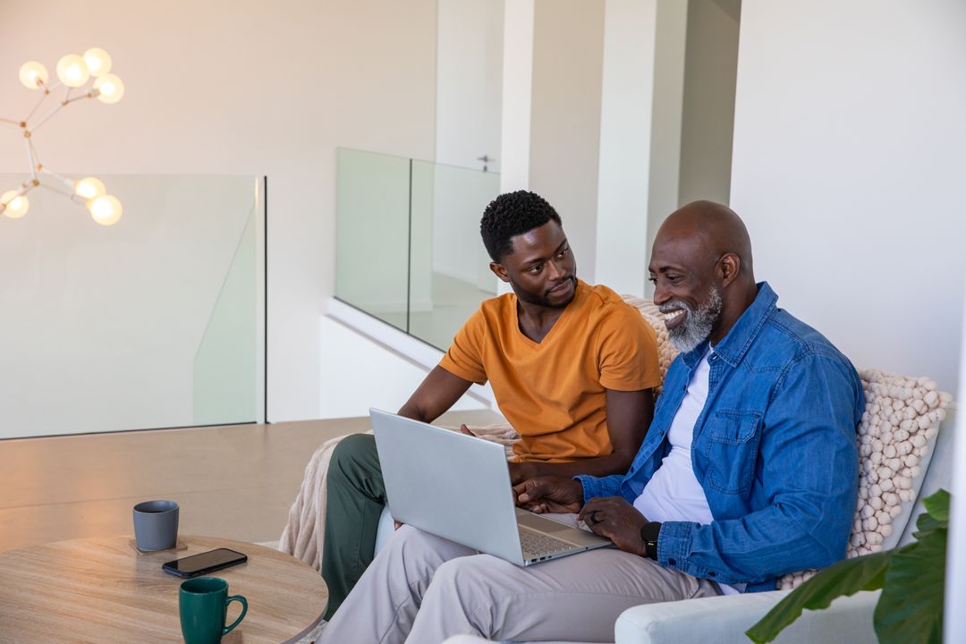 Father and Son Collaborate on Laptop at Home