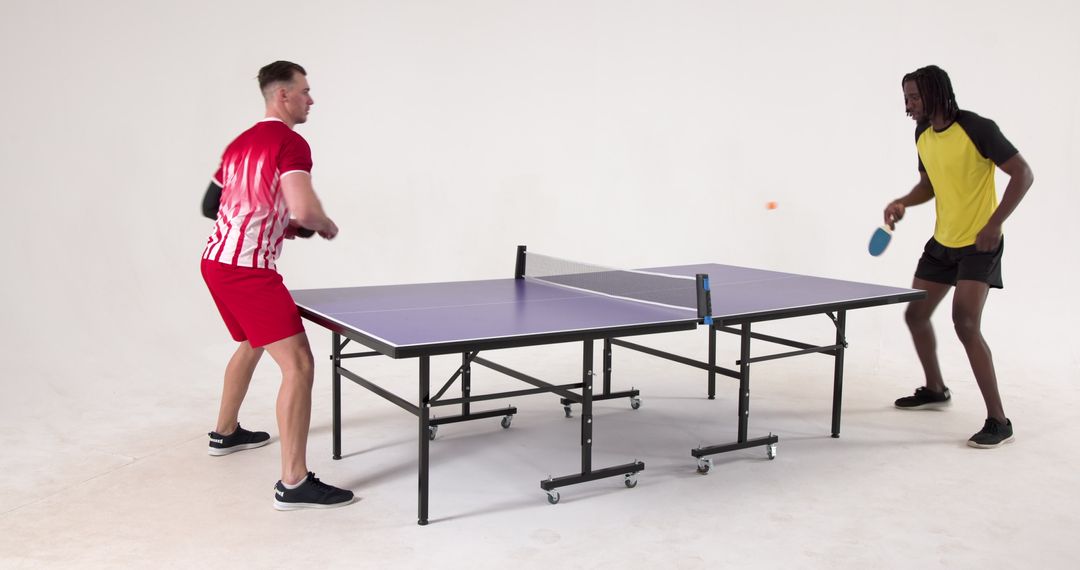 Diverse Friends Enjoying Intense Table Tennis Match in Studio Setting